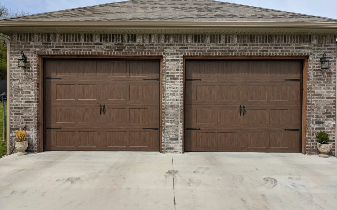 two brown garage doors on a brick building